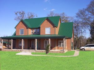 Rural home with steel log siding and green metal roof.