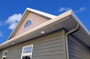 Beige colored home with prominent white gutters.