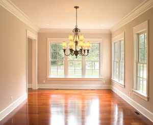 A Bright, Unfurnished Room With a Chandelier and Natural Light Pouring in Through Windows