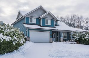 A suburban home with blue siding on a snowy day