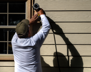 A contractor works to install siding on a home.