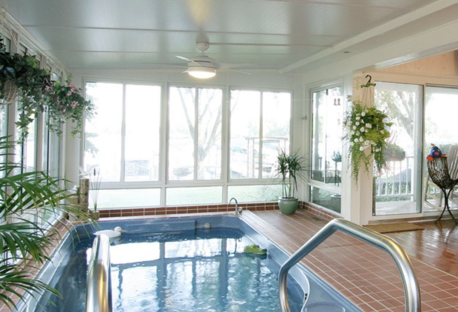 a sunroom style hot tub enclosure with in-ground spa