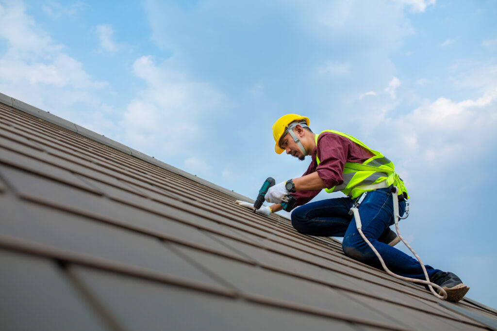 Construction Workers Fixing Roof Tiles With Roofing Tools Elec - ABC Seamless of Nebraska Omaha roofing contractor installing metal roof